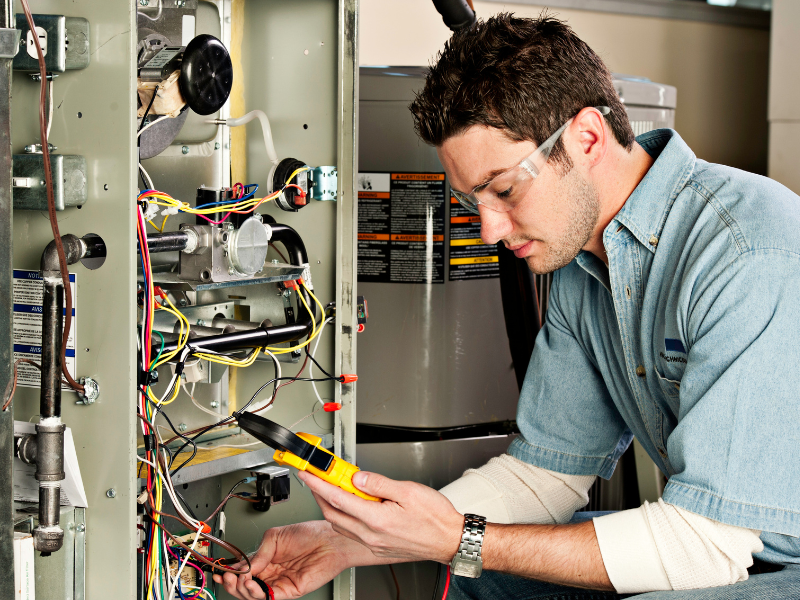 Image of an HVAC technician attending to a furnace service appointment.