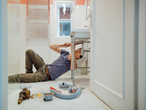 An Edmonton homeowner attempting a DYI plumbing job. DIY vs. Professional Plumbing: When to Call an Expert.