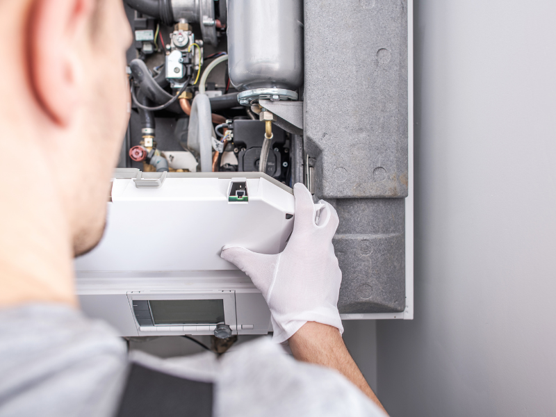 A Habberjam At Home HVAC technician inspecting a furnace in an Edmonton home.