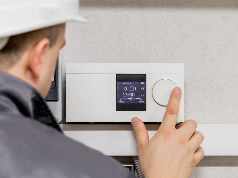 A Habberjam At Home HVAC technician installing a smart thermostat in an Edmonton home. What Homeowners Need to Know About Smart Thermostats.