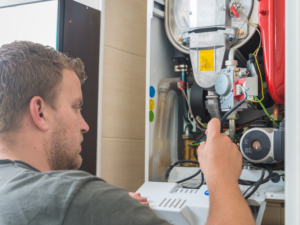 A Habberjam At Home HVAC technician inspecting a furnace inside an Edmonton home. Know When To Replace Your Furnace.