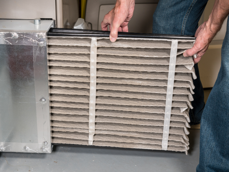 Homeowner changing the air filter in an HVAC unit. A complete HVAC system maintenance checklist.