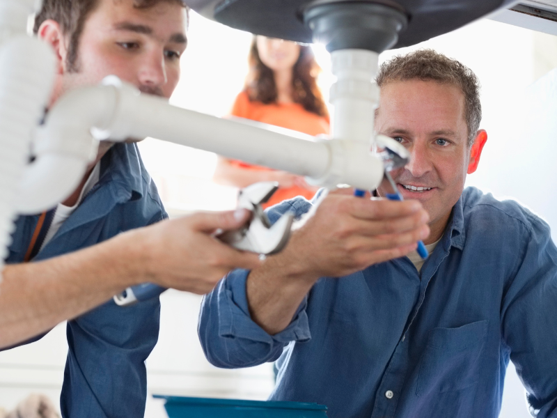 Edmonton homeowner watching a plumber inspect pipes, symbolizing common plumbing myths.