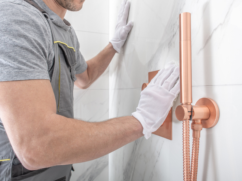 A plumber installing a modern low-flow shower that disperses water efficiently.